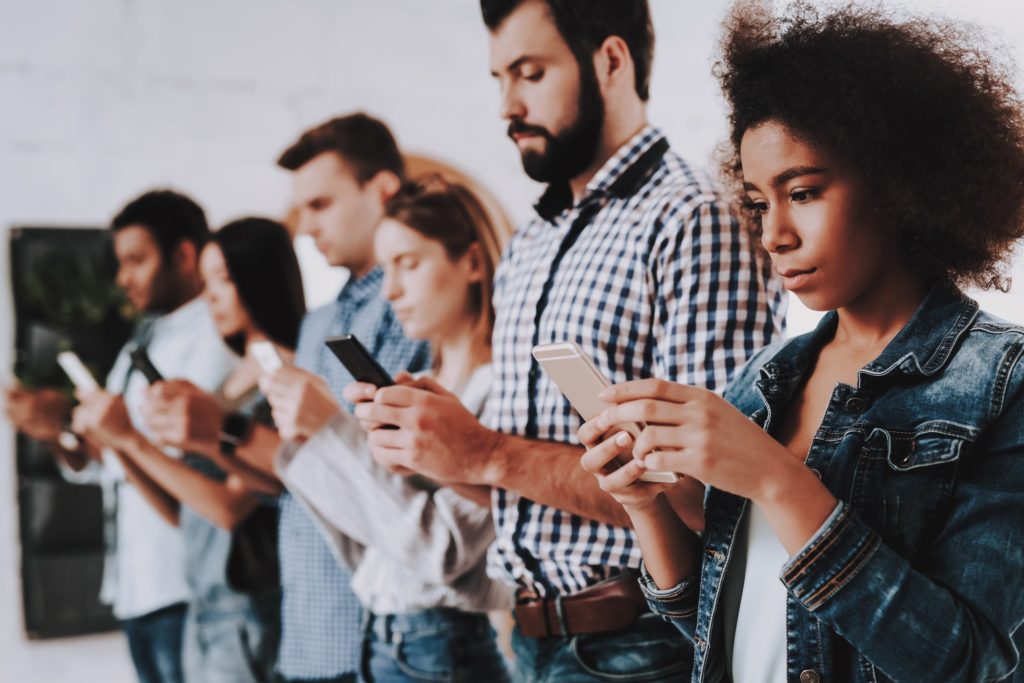 Young people standing in line on their phones. 
