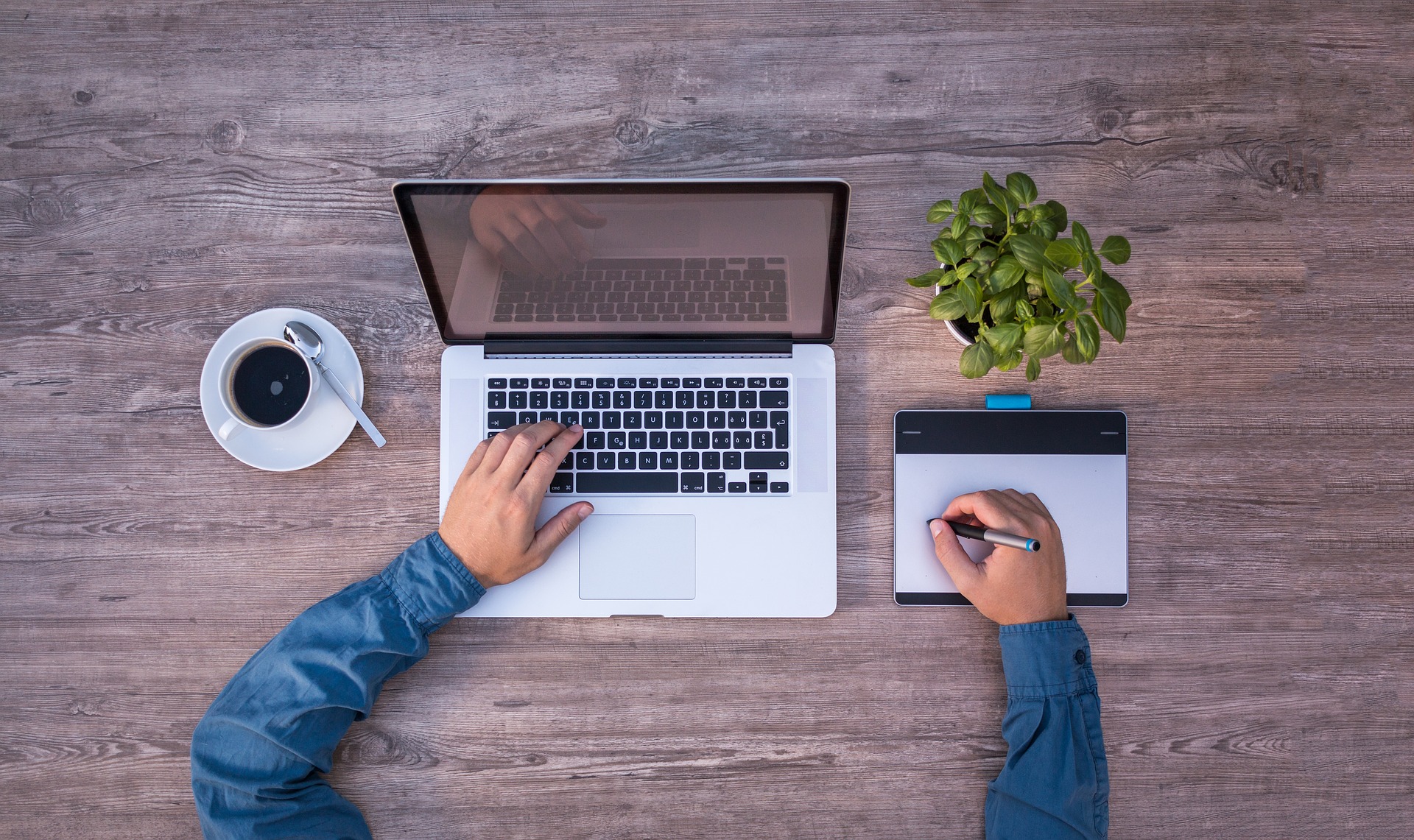 Man sitting at large desk with his laptop and a cup of coffee.